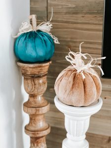 two dollar tree pumpkins sitting on top of two candle sticks for fall